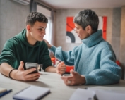 Teenage son and mom talking together at a table.