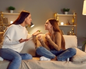 Mother is sitting on a sofa arguing with her teen daughter.