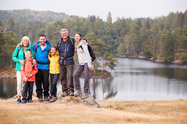 Several generations of a family with backpacks standing by a mountain lake.