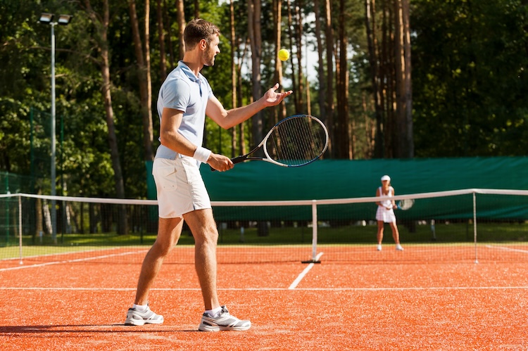 Man preparing to serve a tennis ball to his opponent across the net.