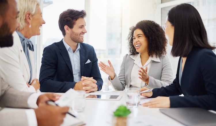 Group of adults sitting around the table meeting and laughing.