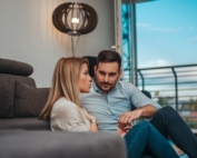 Man and woman seated by each other, carefully listening to each other.