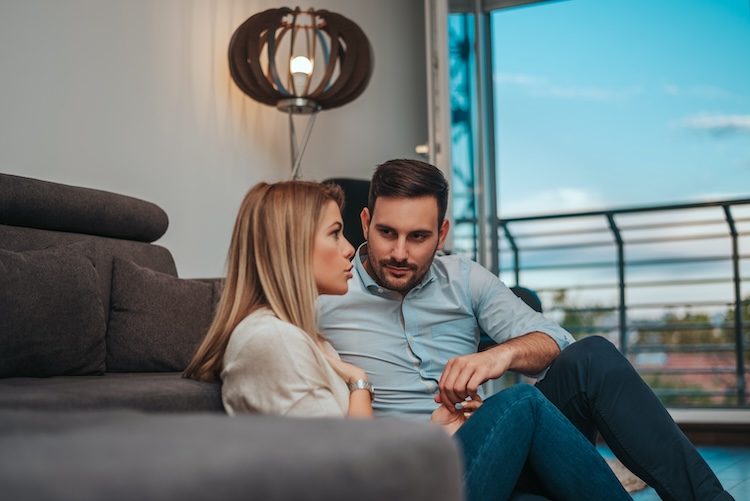 Man and woman seated by each other, carefully listening to each other.