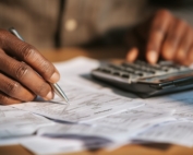 Person using a calculator as they look over piles of tax documents.