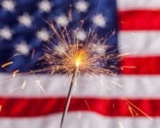 Fourth of July sparkler in front of the US flag.