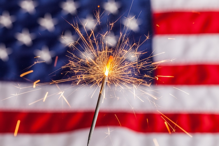 Fourth of July sparkler in front of the US flag.