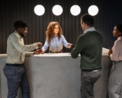 Female receptionist interacting with several people at her desk.