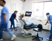 Dentist office with lots of busy workers caring for patient.