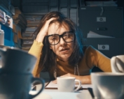 Frustrated woman sitting at a desk piled high with work and papers.